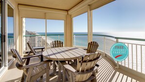 A covered outdoor area with a table and chairs, a view of the ocean, and a sign indicating free covered parking.