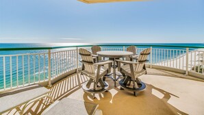 Een balkon met een tafel en stoelen, met uitzicht op het strand.