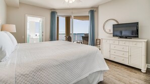 Een hotelkamer met een bed, een televisie, een dressoir en een balkon met uitzicht.