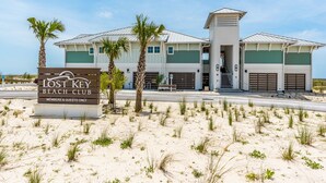 A beach club with a signboard, palm trees, and a building with a green and white color scheme. - Lost Key Villas Golf & Beach Club ~CS'ta on the Key -  NO HASSLE CHECK OUT (Pensacola)