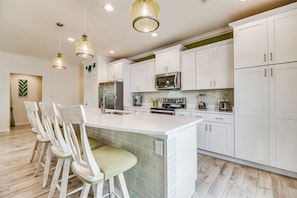 A modern kitchen with white cabinets, a central island, and a dining area with chairs. - Lost Key Villas Golf & Beach Club ~CS'ta on the Key - NO HASSLE CHECK OUT (Pensacola)