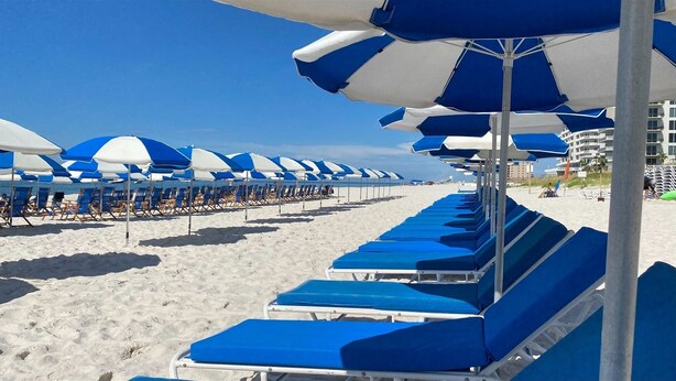A beach with rows of blue and white striped umbrellas and lounge chairs. - Escape at Lost Key Golf & Beach Club ~ Escape - NO HASSLE CHECK OUT (Pensacola)