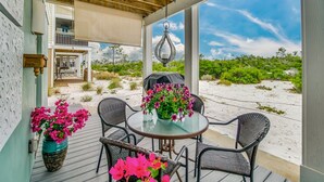 A covered outdoor seating area with a table and chairs, overlooking a sandy landscape with greenery. - Lost Key Townhomes 14274 ~ Flip Flop Stop  -  NO HASSLE CHECK OUT (Pensacola)