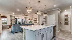 A spacious kitchen with a central island, pendant lighting, and a dining area with a blue sofa. - Lost Key Townhomes 14274 ~ Flip Flop Stop  -  NO HASSLE CHECK OUT (Pensacola)