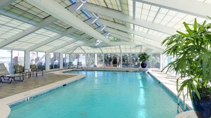 Ein Innenpool mit Glasdecke, Liegestühlen und Topfpflanzen.
