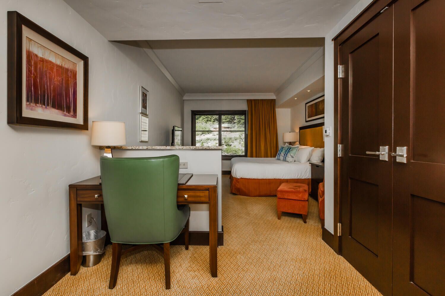 Ein Hotelzimmer mit Schreibtisch, Stuhl, Bett und Kleiderschrank.
