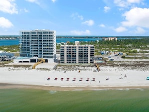 A beachfront hotel with multiple floors, a pool, and beach umbrellas.