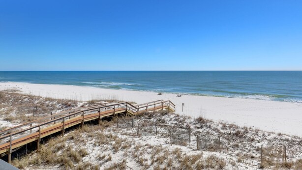 A beach with a wooden boardwalk leading to the shore.