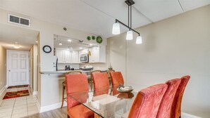 A modern kitchen with white cabinets, a microwave, and a clock on the wall.