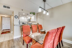 Een moderne keuken met witte kasten, een magnetron en een klok aan de muur.