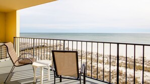 Un balcón con vista a la playa, que incluye dos sillas y una mesita.