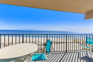 Un balcone con tavolo e sedie, vista su una spiaggia sabbiosa e l'oceano.