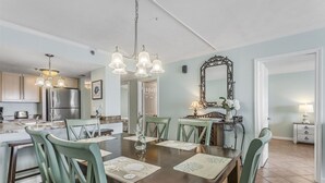 A dining area with a wooden table, green chairs, and a chandelier.