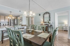 A dining area with a wooden table, green chairs, and a chandelier. - NEW LISTING!!! Ocean Breeze West - Beachfront view - NO HASSLE CHECK OUT (Pensacola)