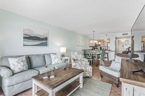 Een woonkamer met een bank, een salontafel en een eethoek met stoelen en een tafel.