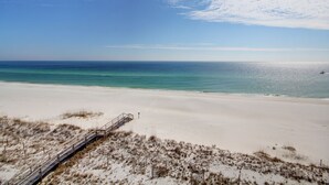 A beach with a wooden boardwalk leading to the water.