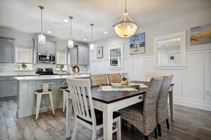 Une cuisine moderne avec des meubles blancs, un îlot central et des luminaires suspendus.