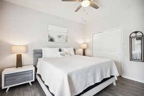 A bedroom with a bed, nightstands, a ceiling fan, a wall-mounted mirror, and a door. - NEW LISTING! Lost Key Golf & Beach Club ~ Pelicans Paradise - NO HASSLE CHECK OU (Perdido Key)