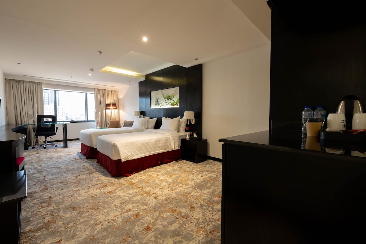 A hotel room with a large bed, two bedside tables, a desk, and a chair.
