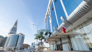 A modern building with a curved facade and a prominent red flag. - MIRA BUSINESS HOTEL (Riyadh)
