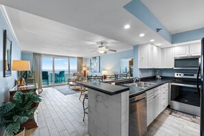 A modern kitchen with a large island, stainless steel appliances, and a view to the outside.