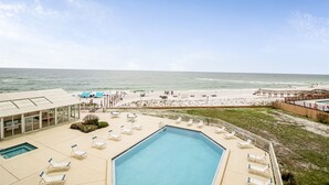 A pool area with lounge chairs, a view of the beach, and a wooden deck. - Perdido Sun 1004 - indoor pool - Beachfront - NO HASSLE CHECK OUT (Perdido Key)