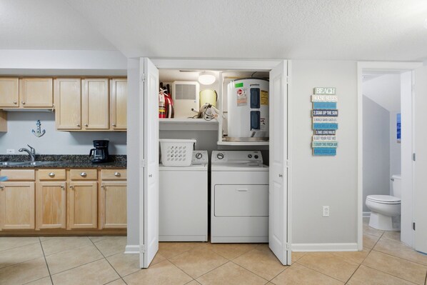 A laundry room with two washing machines, a dryer, and a water heater.