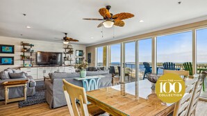 A spacious living room with a large dining table, comfortable seating, a kitchen area, and a balcony with a view. - SAILMAKER 1001 - Ole River Views -NO HASSLE CHECK OUT (Pensacola)