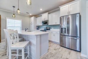 A modern kitchen with white cabinetry, stainless steel appliances, and a central island with seating.