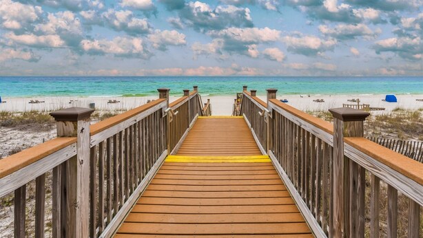 A wooden boardwalk leading to a beach with clear turquoise water and white sand. - Sandy Key 227 Second floor -Beachfront view -NO HASSLE CHECK OUT (Pensacola)
