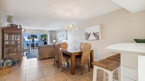A modern living room with a dining area, a kitchen, and a balcony with a view of the ocean. - Sandy Key 227 Second floor -Beachfront view -NO HASSLE CHECK OUT (Pensacola)