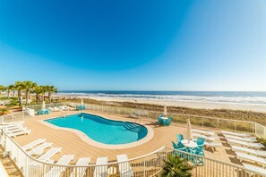 A pool area with a view of the beach, surrounded by lounge chairs and umbrellas. - Sandy Key 233 Second floor -Beachfront view -NO HASSLE CHECK OUT (Perdido Key)