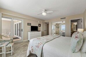 A bedroom with a bed, a dresser, a television, and a ceiling fan.