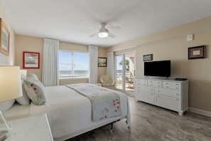 Une chambre à coucher comprenant un lit, une commode, un téléviseur et un ventilateur de plafond.