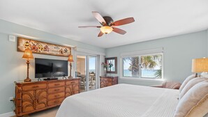A bedroom with a large bed, a ceiling fan, a TV, and a wooden dresser. - Sandy Key 236 Second floor -Beachfront view -NO HASSLE CHECK OUT (Pensacola)