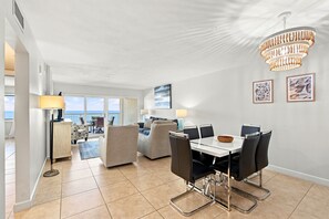 Ein geräumiger Wohnbereich mit Esstisch, Stühlen und einer Chandelüster.