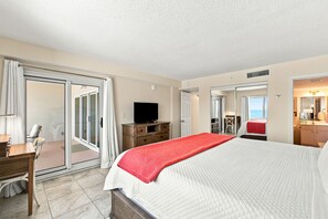 Ein Hotelzimmer mit einem Bett, einem Fernseher, einem Schreibtisch und einem Badezimmer mit Spiegel.