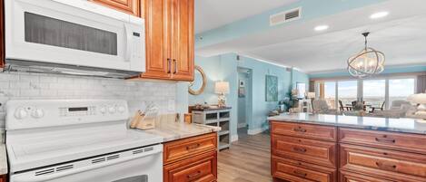 A kitchen with wooden cabinets, a white stove, and a large island with drawers.