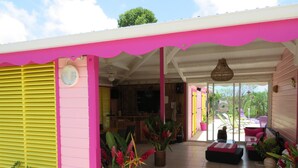 Ein helles, rosa und gelbes Interieur mit Fliesenboden, einem Essbereich und Blick nach draußen.