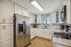 Enjoy cooking in this well-lit kitchen with a gas stove, microwave, and stainless steel refrigerator.