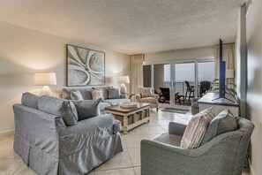Relax in this stylish living room with a comfortable sofa, flat-screen TV, and sliding glass door leading to a balcony with outdoor seating.