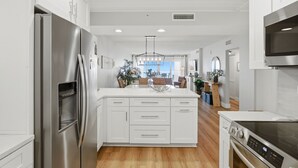 A modern kitchen with white cabinetry, stainless steel appliances, and a central island.