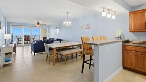A spacious living area with a dining table, chairs, and a kitchen island. - Sandy Key  637 6th floor -Beachfront view -NO HASSLE CHECK OUT (Pensacola)