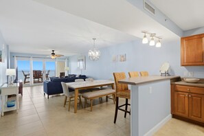 Ampla sala de estar com mesa de jantar, cadeiras e bancada na cozinha.