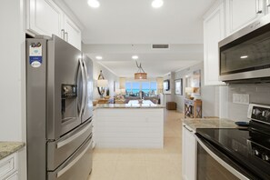 Una cocina moderna con electrodomésticos de acero inoxidable, una isla central y vistas al salón.