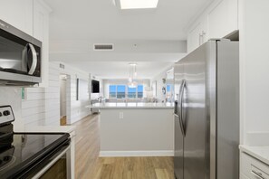 A modern kitchen with a central island, stainless steel appliances, and a view to the outside. - Sandy Key 827 -8th floor -Beachfront view -NO HASSLE CHECK OUT (Pensacola)