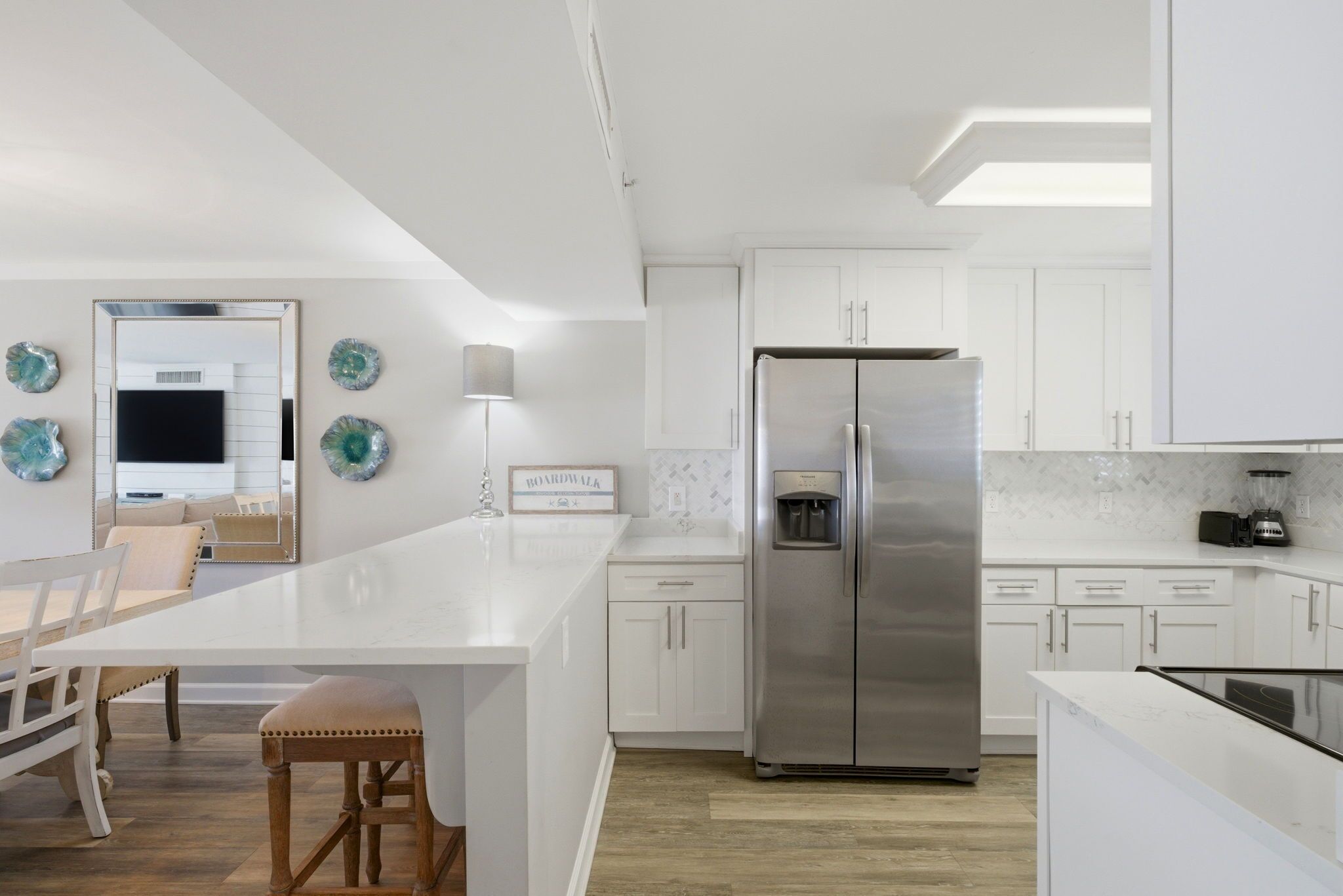 A modern kitchen with white cabinetry, a stainless steel refrigerator, and a central island with seating.