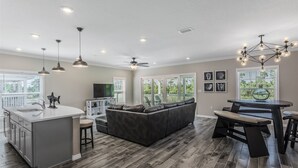 A modern kitchen with a central island, a dark leather sofa, and a dining area with a bar. - NEW LISTING! Lost Key Villas Golf & Beach Club ~Sea Salt - NO HASSLE CHECK OUT (Perdido Key)