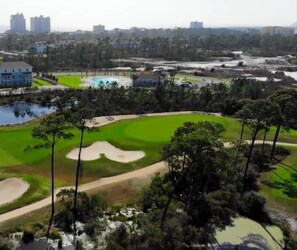 Un parcours de golf avec des bunkers de sable, un étang et des arbres tout autour.