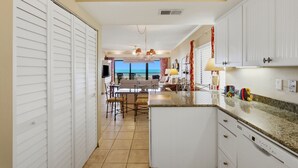 A kitchen with white cabinets, a granite countertop, and a view to the outside.